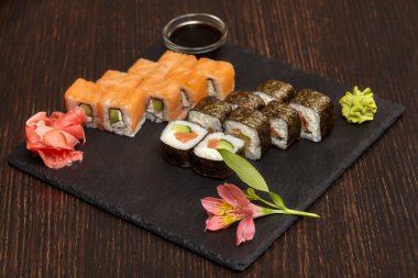 Kümeleri suşi rulo siyah arduvaz plaka üzerinde