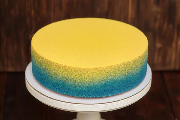 Torta blu e gialla su basamento su fondo di legno — Foto Stock