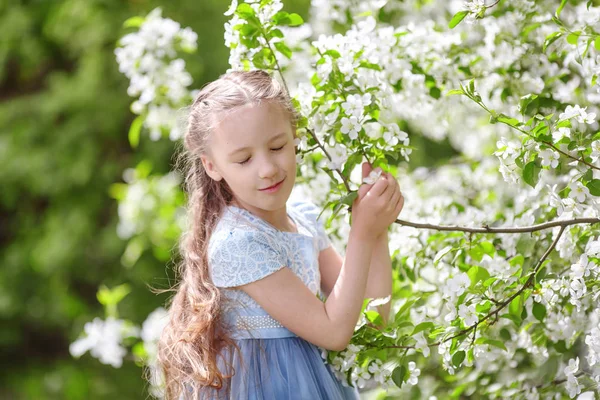 Милая маленькая девочка в цветущем саду яблони весной — стоковое фото