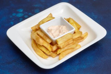 Fastfood. Beyaz tabak, mavi zemin üzerine patates kızartması