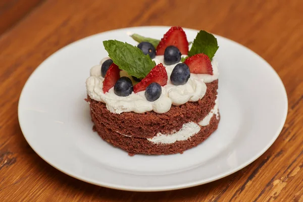 Ciasto czekoladowe z kremem i jagód na białym talerzu — Zdjęcie stockowe