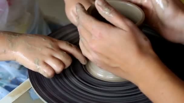 Handen van twee mensen maken pot, pottenbakkers wiel. Onderwijs aardewerk — Stockvideo