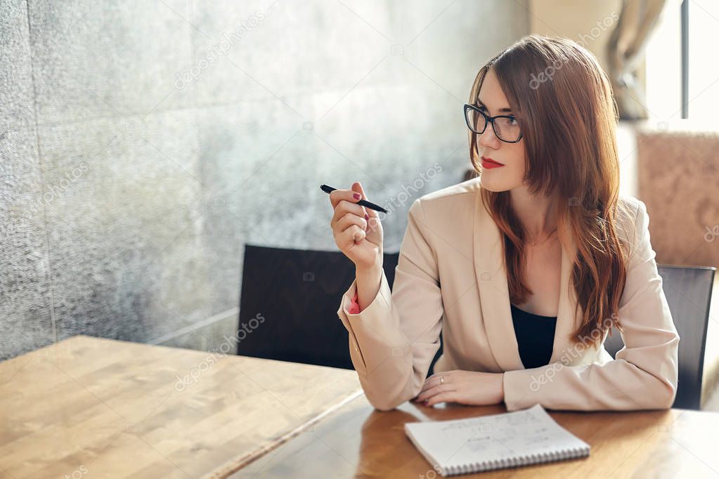 Young caucasian businesswoman with notebook. Woman in glasses in a cafe