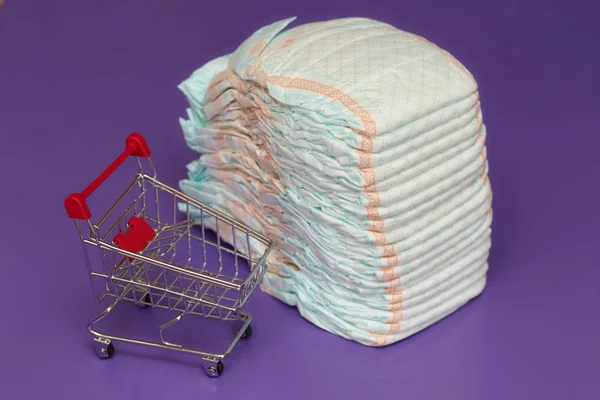 Pilha de fraldas ou fraldas e carrinho de compras mini, conceito — Fotografia de Stock