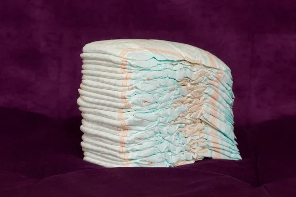 Stack of diapers or nappies on purple background — Stock Photo, Image