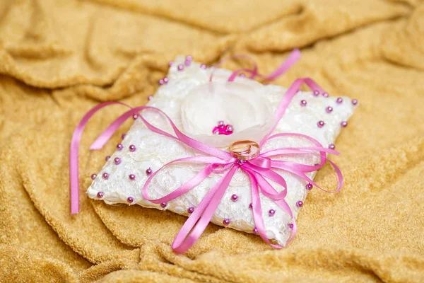 Anneaux de mariage dorés sur petit oreiller blanc décoré — Photo