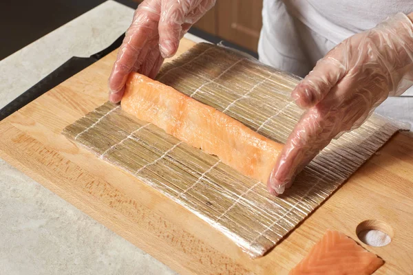 Chef making sushi. Preparing rolls with salmon