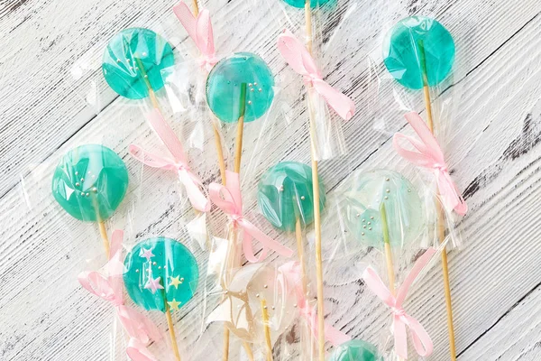 Pirulitos doces verdes na xícara no fundo de madeira branco — Fotografia de Stock