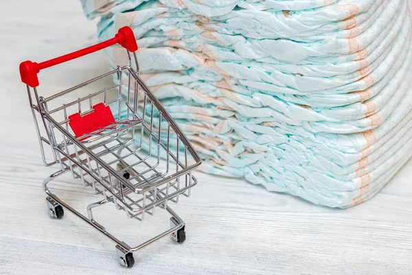 Pila de pañales o pañales y mini carrito de compras, concepto —  Fotos de Stock