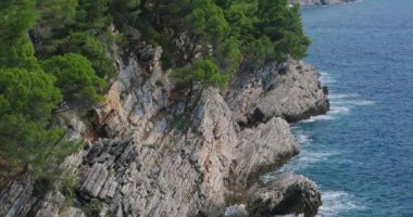 Kayalar ve mavi dalgalı deniz yüzeyi, üst görünümü. Güzel doğal arka plan 4k