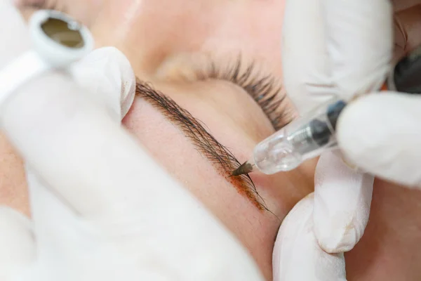 Permanent makeup, tattooing of eyebrows. Cosmetologist applying make up