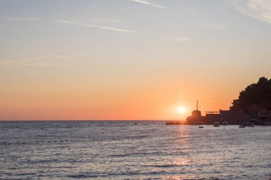 Gün batımında kıyıda. Karanlık deniz yüzeyi ve güneş yansıması.