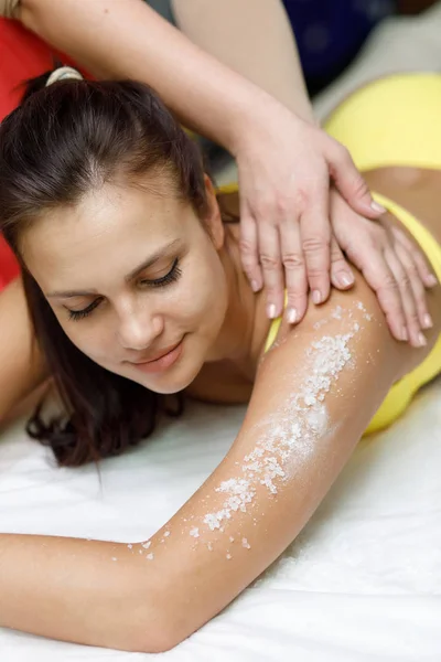 Kobieta brunetka otrzymywać sól peeling leczenie w spa salon — Zdjęcie stockowe