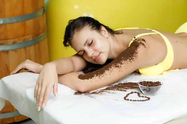 Mulher morena recebendo tratamento de esfoliação de café no salão de spa — Fotografia de Stock