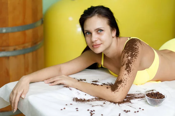 Mulher morena recebendo tratamento de esfoliação de café no salão de spa — Fotografia de Stock