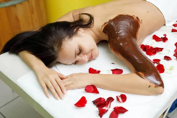 Massagista a aplicar chocolate nas costas da mulher. Massagem no salão de spa — Fotografia de Stock