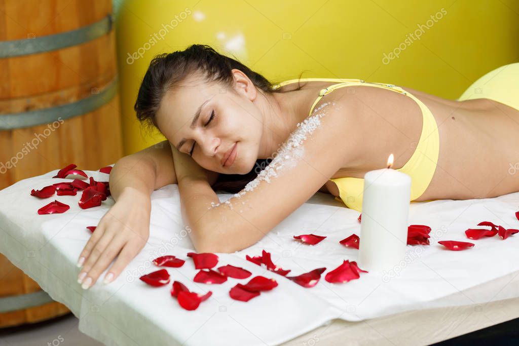 Woman brunette getting salt scrub treatment in spa salon
