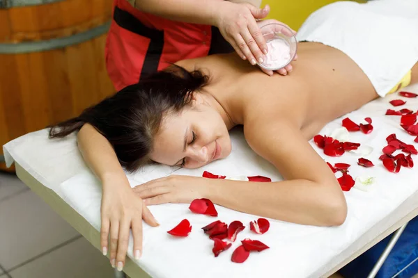 Massagista a aplicar creme nas costas da mulher. Massagem no salão de spa — Fotografia de Stock