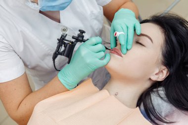 Güzellik salonunda dudaklarında kalıcı makyaj yapan bir kadın.