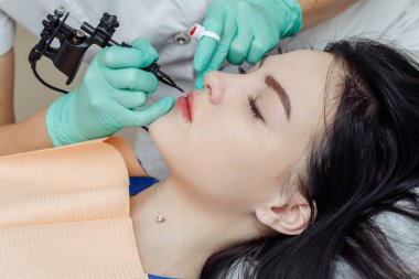 Güzellik salonunda dudaklarında kalıcı makyaj yapan bir kadın.