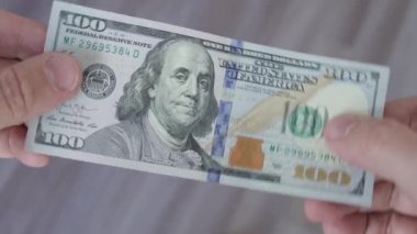 Adam 100 dolarlık banknot tutuyor. Paralı erkek eller, yakın plan.