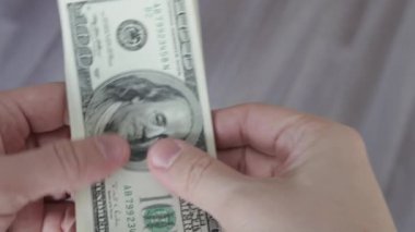 Adam 100 dolarlık banknotları sayıyor. Erkek eli kapalı para saymak