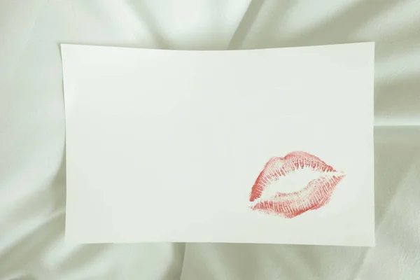 sexy red lipstick kiss on blank white note. white bed pillow sheet in the morning light, valentine's day.