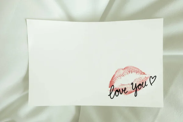 Sexy rossetto rosso bacio 'ti amo' cuore sulla nota bianca. lenzuolo da letto bianco alla luce del mattino, San Valentino . — Foto Stock