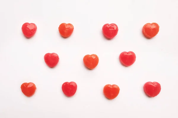 Zwei rot orange Valentinstag Herzen Form Bonbons auf weißem Papier Hintergrund. Liebe. Minimalismus. Hügelige Draufsicht. — Stockfoto