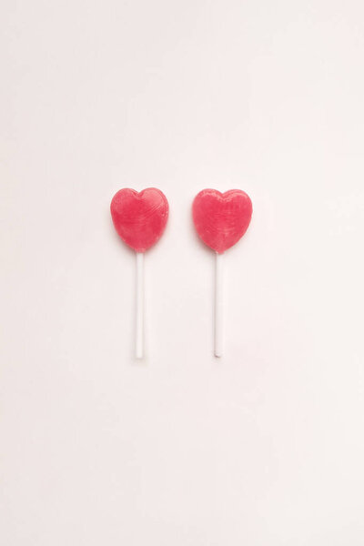 две конфеты в форме сердечка на пустом белом бумажном фоне. Концепция любви. Ноллинг вид сверху. Минимализм красочный хипстерский стиль
.