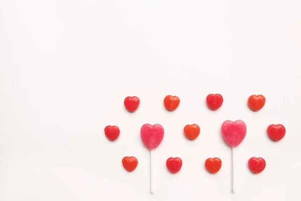 Roze Valentijnsdag hart vorm lolly met kleine rode snoep in leuke patroon op de achtergrond van leeg Witboek. Concept van de liefde. kleurrijke hipster stijl. Bovenaanzicht van de knolling. Rechtenvrije Stockfoto's