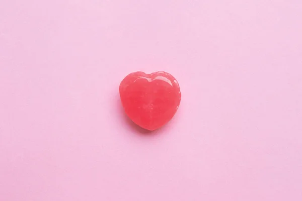 Einzelner rosa Valentinstag Herzform Bonbons auf leerem pastellrosa Papier Hintergrund. Liebe. Ansicht von oben. Minimalismus bunten Hipster-Stil. — Stockfoto