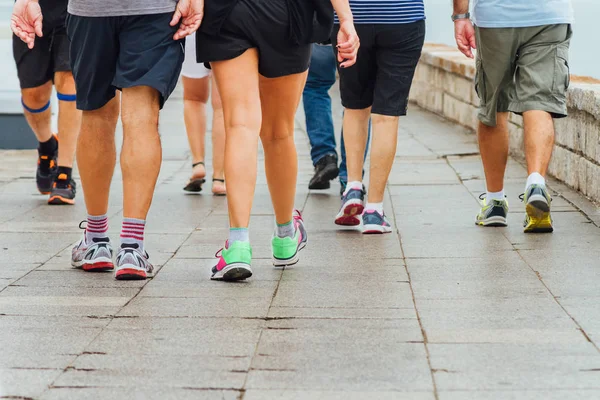 Several people walk down a sidewalk doing exercise