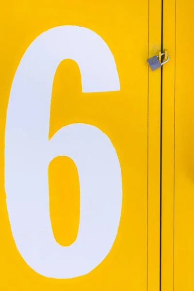 Yellow closed metal gate with padlock with a white number 6