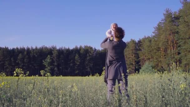 Mãe brincou com o bebê no campo de colza e joga-lo em câmera lenta — Vídeo de Stock