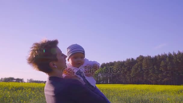 Mãe brincou com o bebê no campo de colza e joga-lo em câmera lenta — Vídeo de Stock