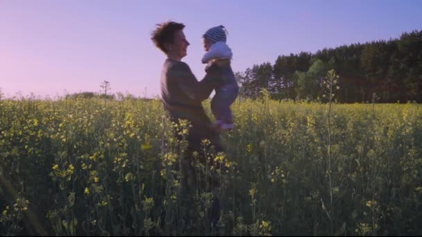 Mamá jugó con el bebé en el campo de colza y lo lanza en cámara lenta — Vídeo de stock