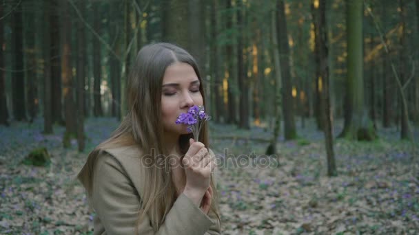Όμορφη νεαρή κοπέλα μυρίζοντας λουλούδια άνοιξης στο δάσος — Αρχείο Βίντεο