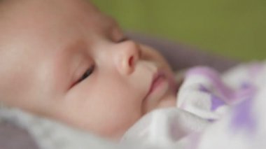 Şirin bir bebek kameraya bakıyor ve beyaz bir çarşaf üzerinde mutlu.