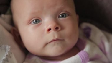 Şirin bir bebek kameraya bakıyor ve beyaz bir çarşaf üzerinde mutlu.