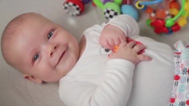 Şirin bir bebek kameraya bakıyor ve beyaz bir çarşaf üzerinde mutlu.