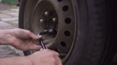 Van üzerinde düz lastik değiştirirken büyük tekerlek cıvata vidalama kirli mekaniği ellerinde yakın odak
