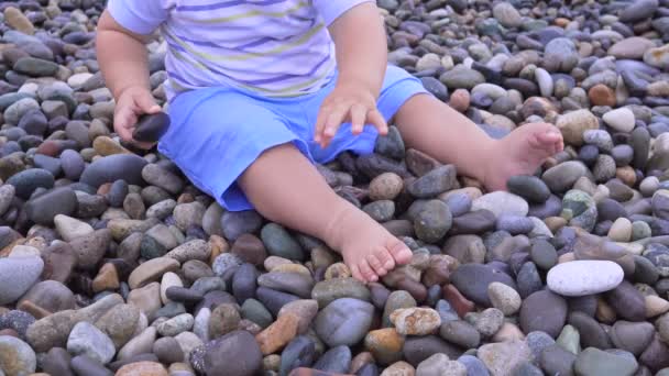 Kleine baby speelt met stenen op het natuurlijke kiezelstrand — Stockvideo
