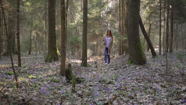 Mooi jong meisje gaat door bos bloemen — Stockvideo