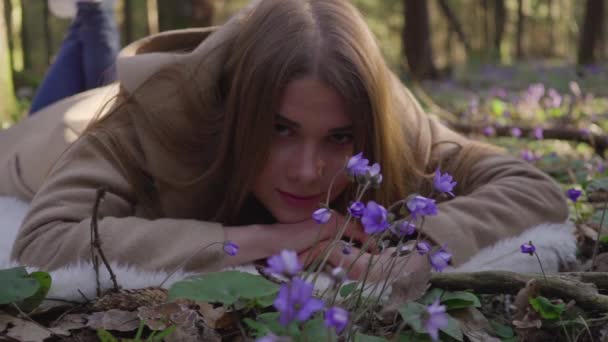 Mooi jong meisje liggend in de bos bloemen — Stockvideo