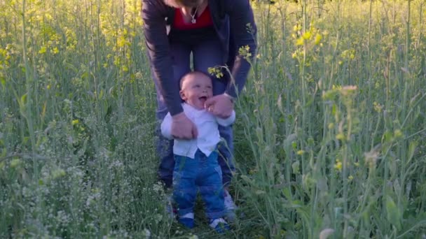 Bebé para aprender a caminar en un campo de colza cámara lenta — Vídeo de stock