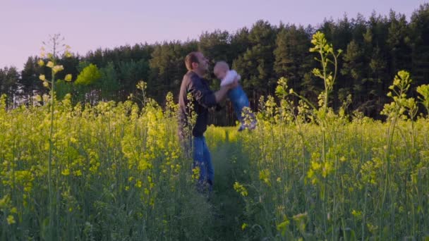 Far spelade med barnet i fältet raps och kastar det Slow motion — Stockvideo