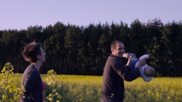 Madre, padre e hijo bailando y jugando en el campo de la colza — Vídeos de Stock