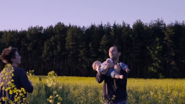 Mãe, pai e filho dançando e brincando no campo de colza — Vídeo de Stock