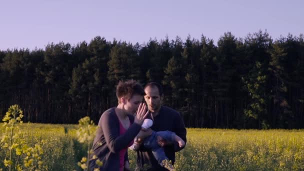 Мать, отец и сын танцуют и играют на поле рапса — стоковое видео